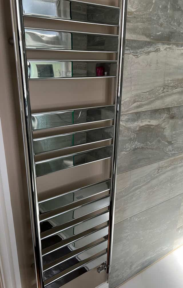 Close-up image of modern vertical chrome radiator installed by Plumb Yorkshire Ltd.