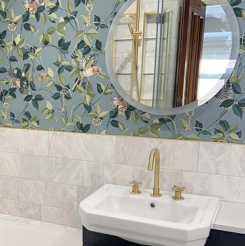 Luxury backlit mirror above sink with brushed gold taps in a stylish floral designed bathroom from Plumb Yorkshire Ltd.