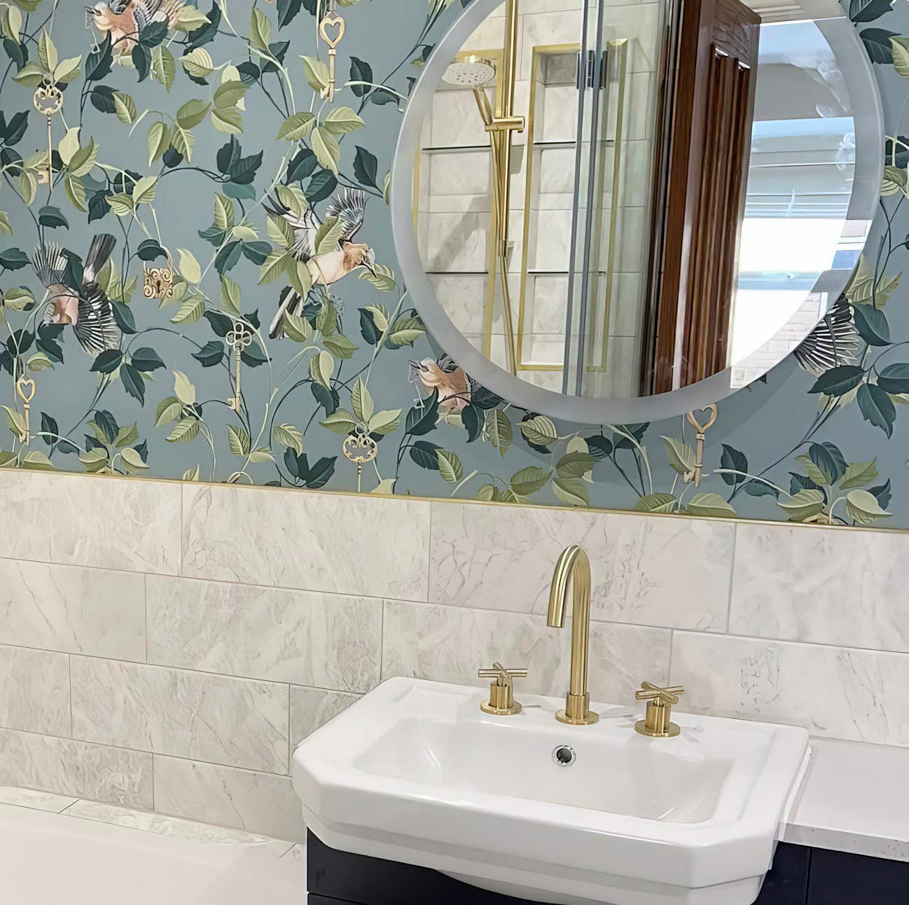 Luxury backlit mirror above sink with brushed gold taps in a stylish floral designed bathroom.