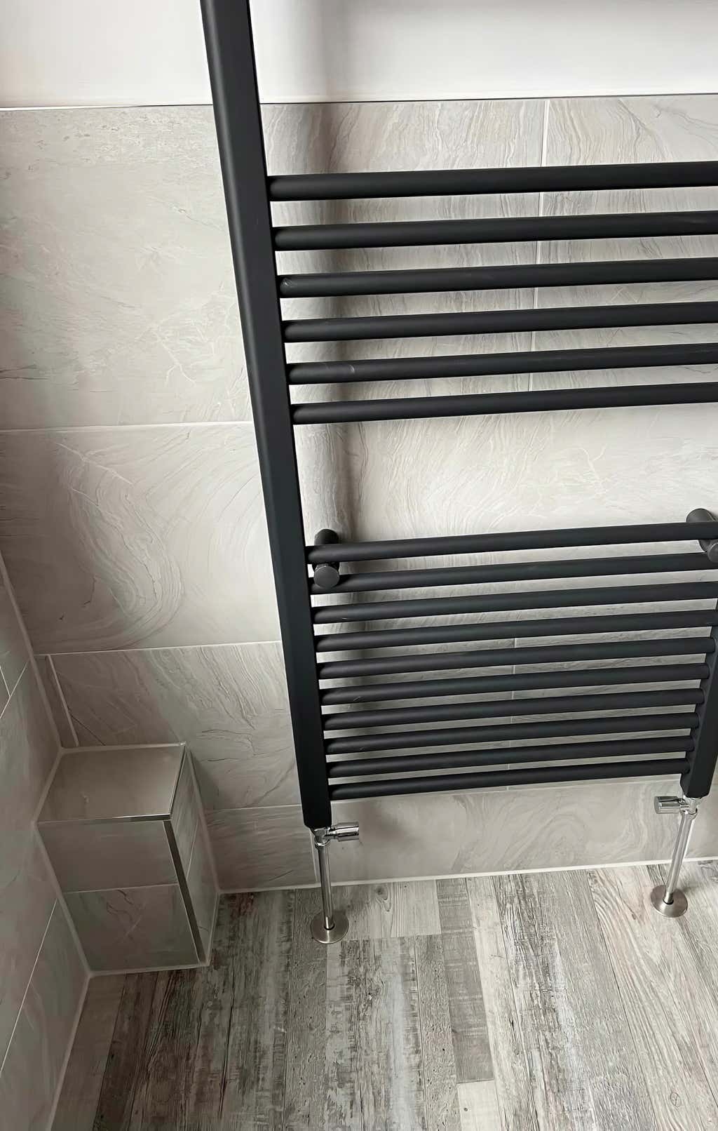 Image of a modern grey vertical radiator in a luxury bathroom created by Plumb Yorkshire Ltd.