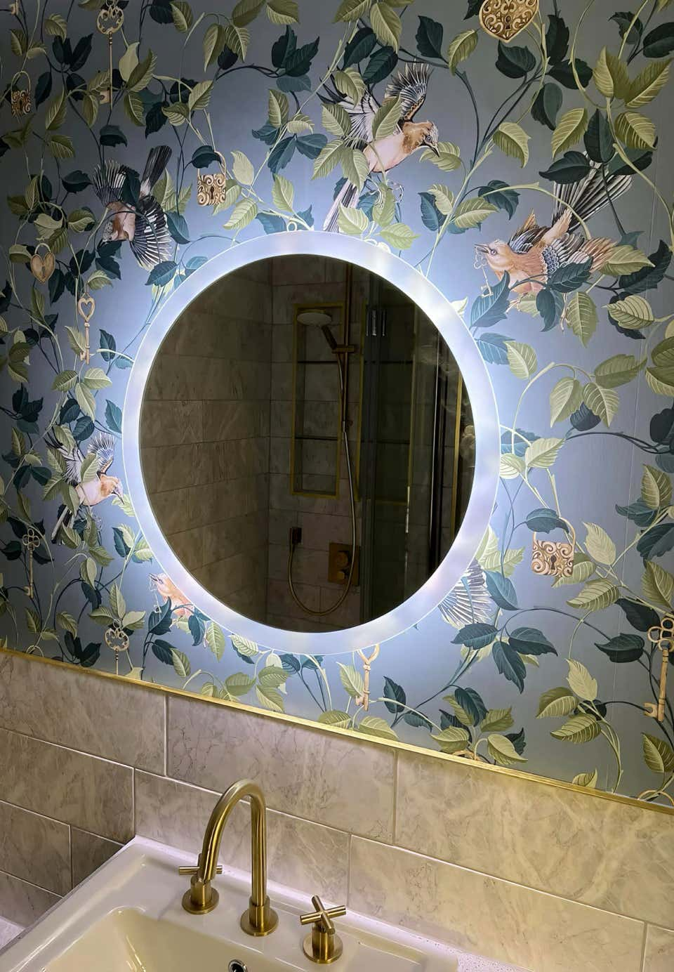 Image of LED illuminated circular mirror above a sink in a stylish bathroom created by Plumb Yorkshire.