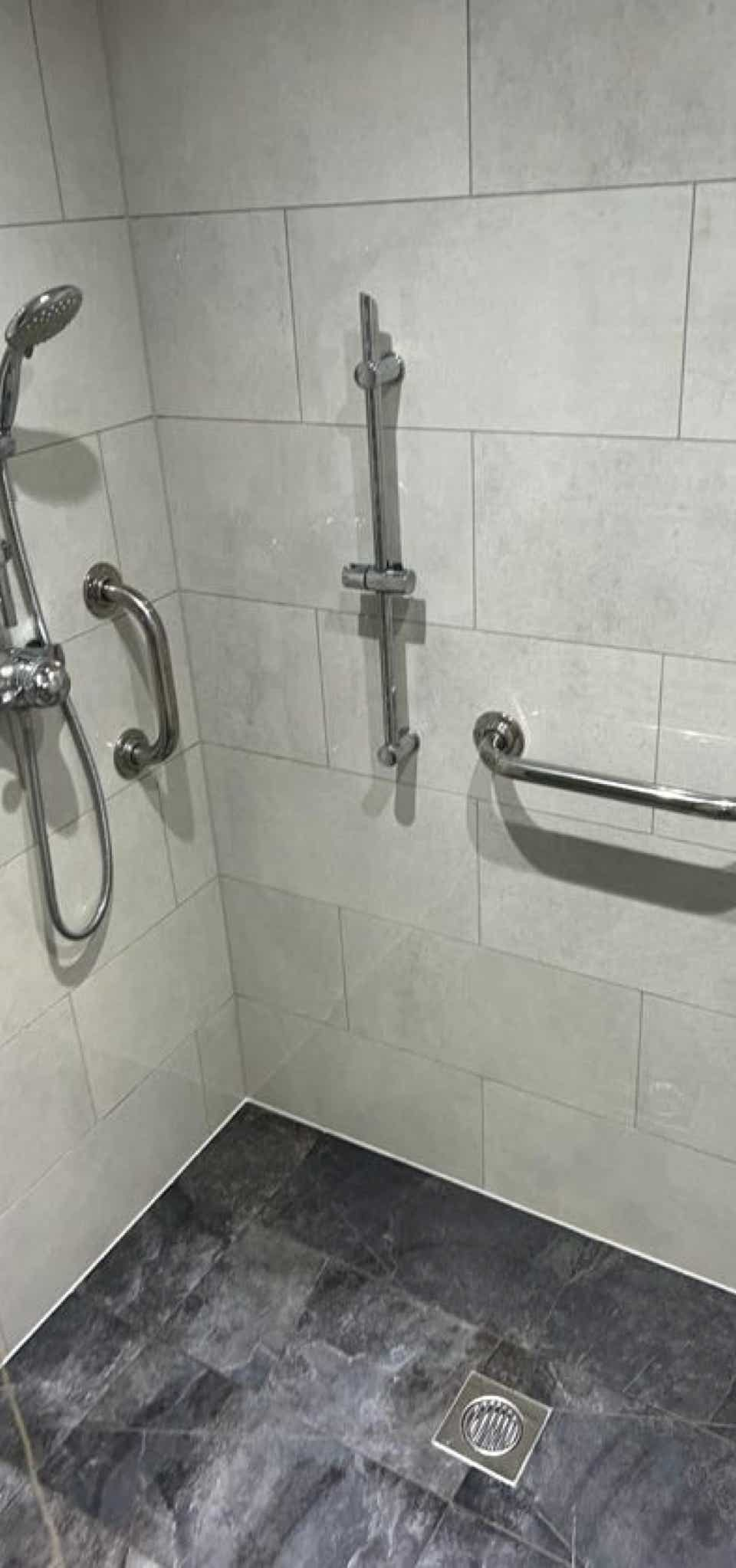 Wet room shower area with mobility fixtures installed by Plumb Yorkshire Ltd.