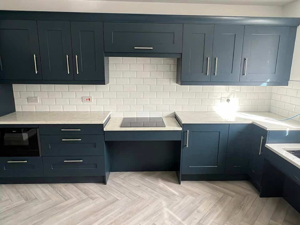 Image of modern kitchen with dark blue cabinets and white tiling.