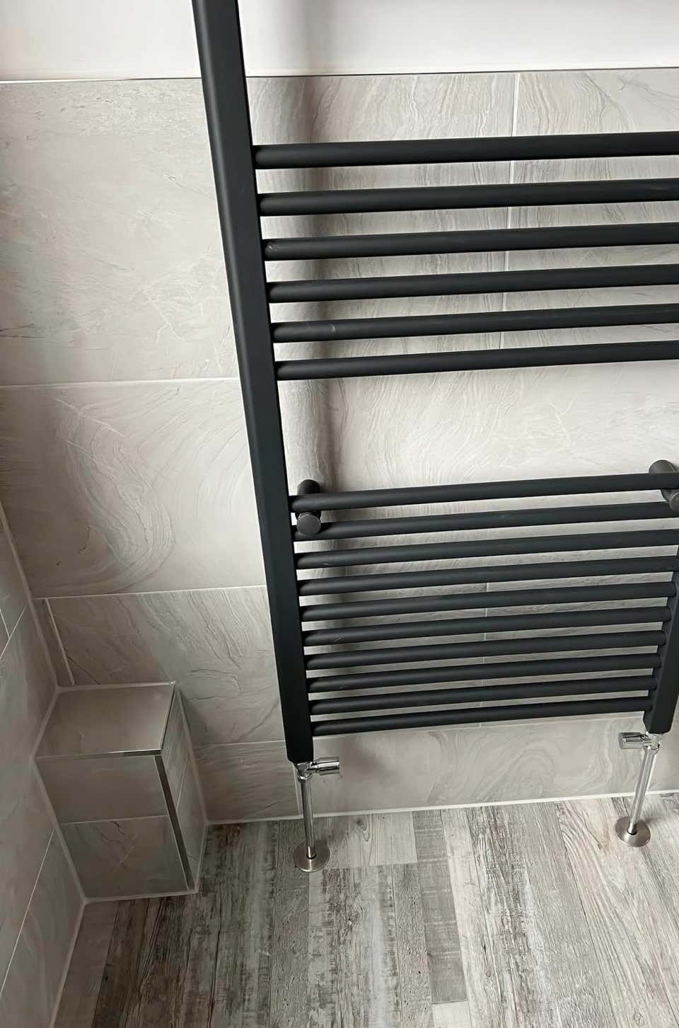 Image of a modern grey vertical radiator in a luxury bathroom created by Plumb Yorkshire Ltd.